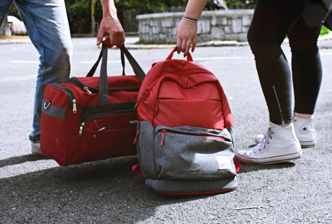 Two people carrying a backpack and duffel bag.