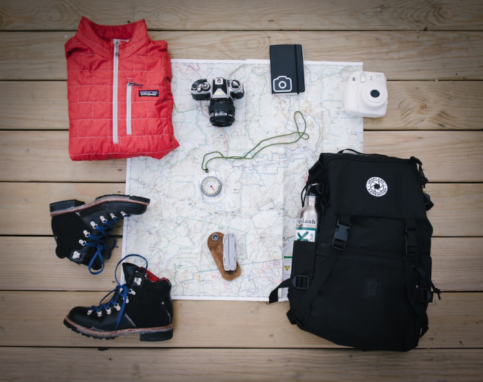 Photo of a jacket, backpack, shoes, gadgets, and map