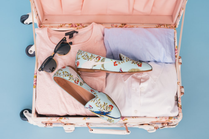 A peach colored suitcase with clothes and accessories