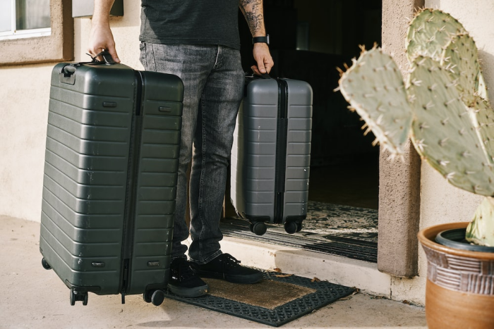 Person holding a small and large suitcase