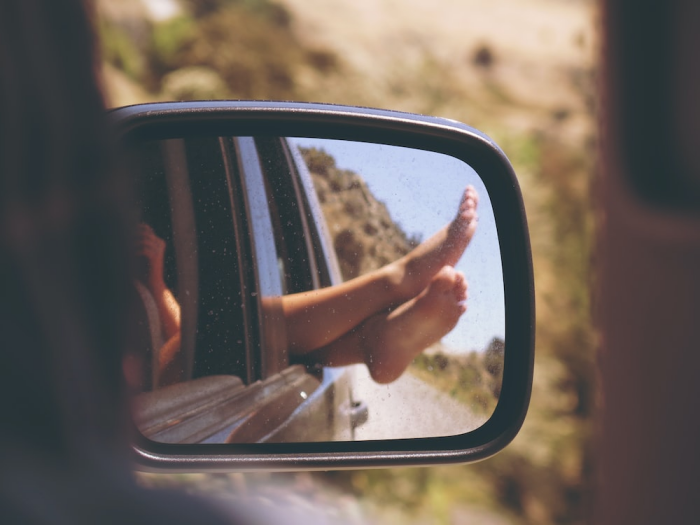 Person’s feet showing in the side mirror of a car