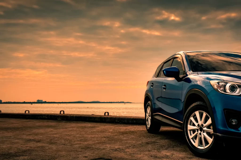 Blue car parked by sunset waterfront