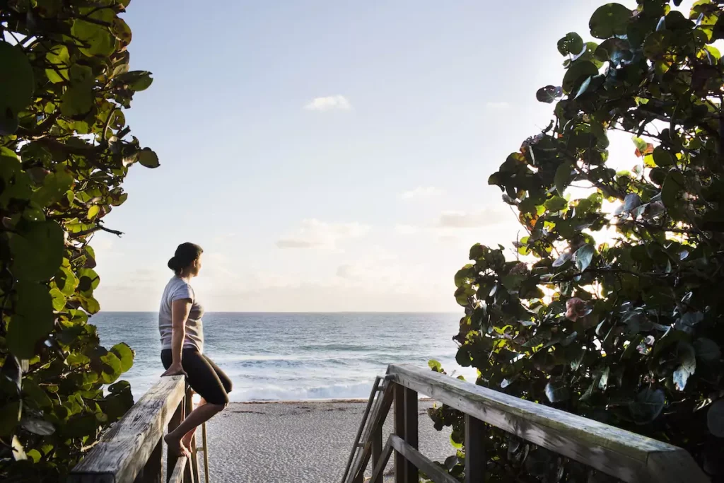 Person sitting, enjoying beach view at sunset.